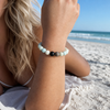 Model wearing amazonite gemstone beaded bracelet on wrist at a Florida Gulf Coast beach