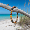 Polychrome jasper gemstone beaded stretch bracelet hanging from driftwood on Florida Gulf Coast beach — 8mm multicolor natural stone beads — Crabby Mermaid
