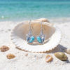 Larimar and cubic zirconia conch shell dangle earrings displayed in open seashell on Florida Gulf Coast beach - genuine Dominican Republic Larimar - Crabby Mermaid