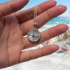 Sterling silver mother of pearl compass pendant held in hand at Florida Gulf Coast beach - 19.5mm wide - handcrafted in Ireland - Crabby Mermaid