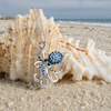 Sterling Silver Octopus Necklace with Blue Crystals displayed against a natural seashell on a sandy beach — Crabby Mermaid