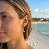 Sterling silver aqua Swarovski crystal whale tail drop earrings closeup on model at Florida beach — Crabby Mermaid