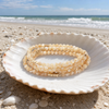 Stone Wrap Mother of Pearl Gold coiled in a seashell on a white sand Florida Gulf Coast beach - Crabby Mermaid