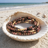 Stone Wrap Rhodochrosite Gold coiled in a seashell on a white sand Florida Gulf Coast beach — Crabby Mermaid