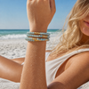 Stone Wrap Blue Howlite Gold worn wrapped on the wrist of a model at a Florida Gulf Coast beach - Crabby Mermaid