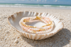 Stone Wrap Pink Opal Gold coiled in a seashell on a white sand Florida Gulf Coast beach — Crabby Mermaid
