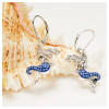 Close-up of sterling silver mermaid drop earrings with sapphire blue crystals displayed on seashell — lever-back closure — handcrafted in Ireland
