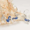 Sterling silver sapphire blue crystal mermaid earrings and matching necklace displayed on seashell - handcrafted in Ireland - Crabby Mermaid