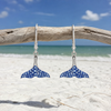 Sterling silver whale tail drop earrings with sapphire blue crystals hanging from driftwood on Florida beach - handcrafted in Ireland - Crabby Mermaid