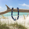 Sterling silver lapis sea turtle bracelet draped over driftwood on Florida Gulf Coast beach - crystal accents - handcrafted in Ireland - Crabby Mermaid