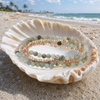 Stone Duo Wrap Rhodochrosite and Labradorite coiled in a seashell on a white sand Florida Gulf Coast beach - Crabby Mermaid