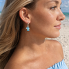 Model wearing teal tassel interchangeable charm earring on silver hoop at Florida Gulf Coast beach - Crabby Mermaid