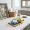 Spongellé Freesia Pear Wild Flower buffer on wooden board with fresh pears on coastal bathroom counter with ocean view — Crabby Mermaid