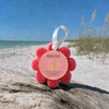Spongellé Grapefruit Cassis Wild Flower buffer on driftwood at Florida Gulf Coast beach with sea oats and turquoise water - Crabby Mermaid