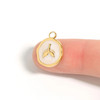 White epoxy whale tail medallion charm in 18K gold PVD finish shown on fingertip for size reference — Crabby Mermaid