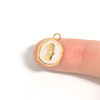 White epoxy seahorse medallion charm in 18K gold PVD finish shown on fingertip for size reference — Crabby Mermaid