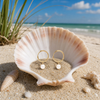 18K gold PVD stainless steel pearl charm hoop earrings resting in seashell on Florida Gulf Coast beach - Crabby Mermaid