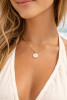 Model wearing gold epoxy whale tail disc charm necklace on Singapore chain - close-up neckline shot