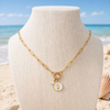 Gold paperclip charm holder necklace with pearl and white epoxy seahorse charm displayed on linen bust with Florida beach background - Crabby Mermaid