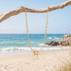 Gold paperclip charm holder necklace with pearl and turtle charms hanging from driftwood on Florida Gulf Coast beach - Crabby Mermaid