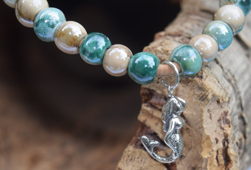Sterling silver mermaid charm suspended from jump ring on teal and beige ceramic bead necklace — Florida artisan jewelry