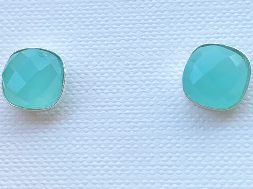 Silver Cushion Aqua Chalcedony Studs Earrings

Ahoy there, mateys! If you're looking for earrings that are as refreshing as a dip in the ocean, then you've come to the right place. Our Silver Cushion Aqua Chalcedony Studs Earrings are the perfect blend of coastal and nautical style, making them a must-have for any beach lover or sea-salt enthusiast.

These earrings are like a little piece of the ocean that you can wear on your ears. The faceted Aqua Chalcedony stones are reminiscent of larimar, the rare and beautiful gemstone found only in the Caribbean. Each stone is unique and varies in size, color, shape, and texture, just like the waves of the ocean.

Crafted from .925 sterling silver, these handmade earrings are both elegant and straightforward, making them the perfect addition to any outfit. Whether you're rocking a sundress or a swimsuit, these earrings will compliment your look and add a touch of oceanic charm.

So, what are you waiting for? Dive into our Silver Cushion Aqua Chalcedony Studs Earrings and let the beachy vibes wash over you. Order now and get ready to make a splash in the world of jewelry!
These ocean-inspired studs are elegant and straightforward and will compliment any outfit.

Each piece will vary in size, color, shape, and texture.

Material .925 Sterling Silver Stone Faceted Aqua Chalcedony

Size Approx 9mm

Handmade in the USA