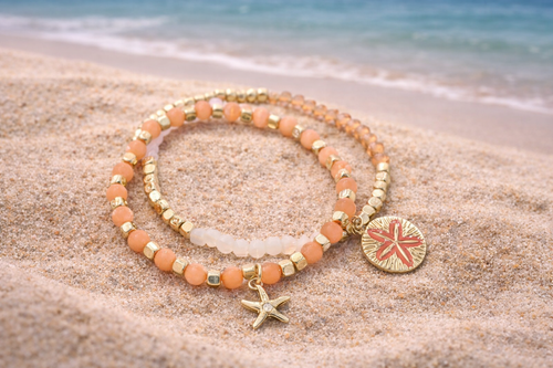 Coral gold beaded bracelet set worn on wrist showing starfish and sand dollar charms - beach jewelry - Crabby Mermaid