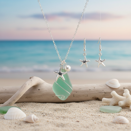 Sea glass style starfish necklace and earring set with pearl accent displayed on driftwood with shells and sea glass on sandy beach — coastal jewelry set — Crabby Mermaid