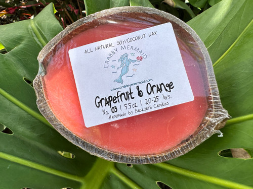 Grapefruit and orange half shell coconut candle with Crabby Mermaid label on tropical leaf background — all natural soy coconut wax — 5.5 oz