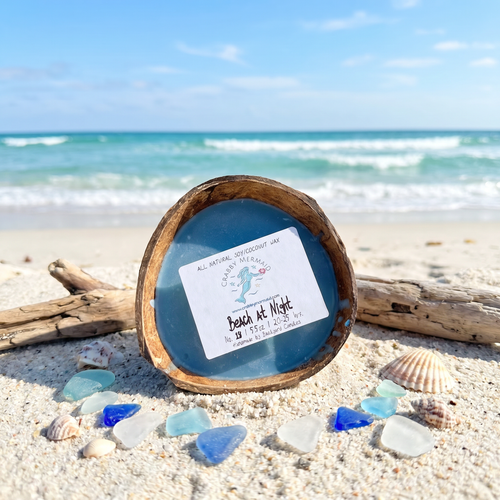 Beach at night coconut shell candle on sandy beach with driftwood and blue sea glass — ocean soy coconut wax candle — Crabby Mermaid