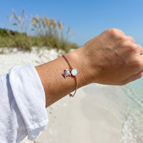 Rose gold plated white opal turtle sterling silver bracelet worn on wrist on Florida Gulf Coast beach ‚Äî Crabby Mermaid