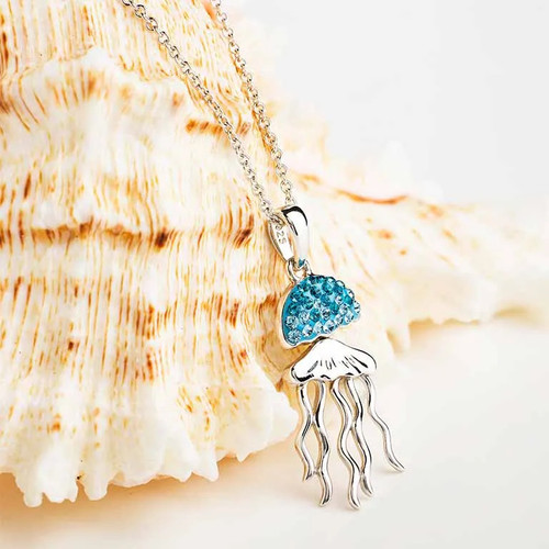 Immerse yourself in the tranquil beauty of our Ocean Serenity Sterling Silver Jellyfish Pendant Necklace. This captivating image showcases the intricately designed pendant with its umbrella-shaped jellyfish head adorned in Aqua Crystals, exuding a sense of inner peace and emotional security. The wavy lines of the tentacles evoke the gentle flow of life's currents, creating a mesmerizing visual harmony. Paired with the .925 Sterling Silver chain, the necklace exudes elegance and style. A symbol of confidence and self-love, this enchanting accessory is your passport to coastal chic. Dive into the allure – click to make the Ocean Serenity yours.