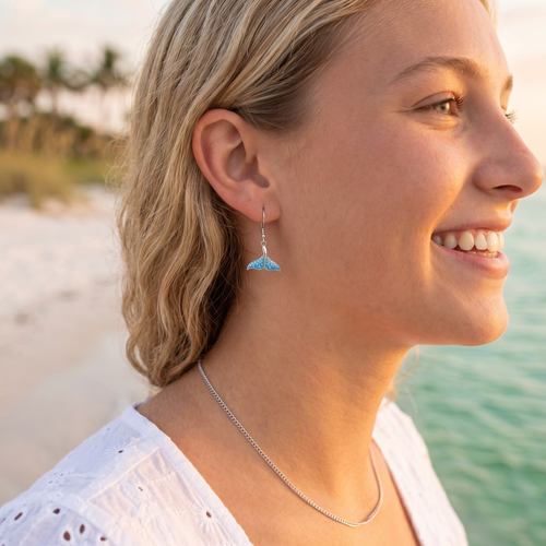 Sterling silver aqua Swarovski crystal whale tail drop earrings worn on model at Florida beach — handcrafted in Ireland — Crabby Mermaid