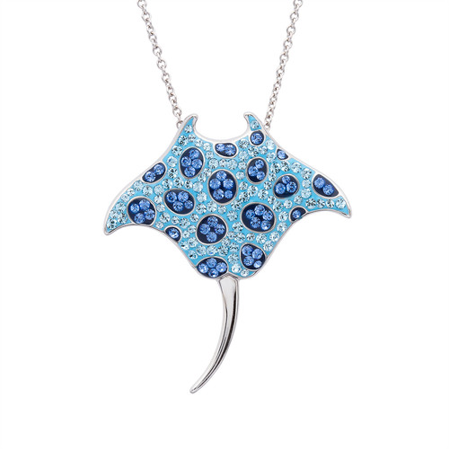 Sterling silver manta ray necklace with aqua and sapphire blue Swarovski crystals against beach background — bold coastal jewelry handcrafted in Ireland