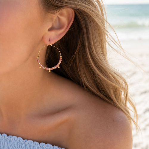Model wearing rhodonite stone disc hoop earrings in gold at Florida Gulf Coast beach - Crabby Mermaid
