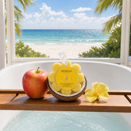 Spongellé Sweet Patchouli Wild Flower buffer on bathtub tray with fresh apple and tropical flower with beach view through window - Crabby Mermaid