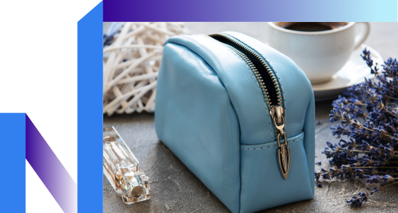 A blue leather purse with a flower next to a steaming cup of coffee on a wooden table.