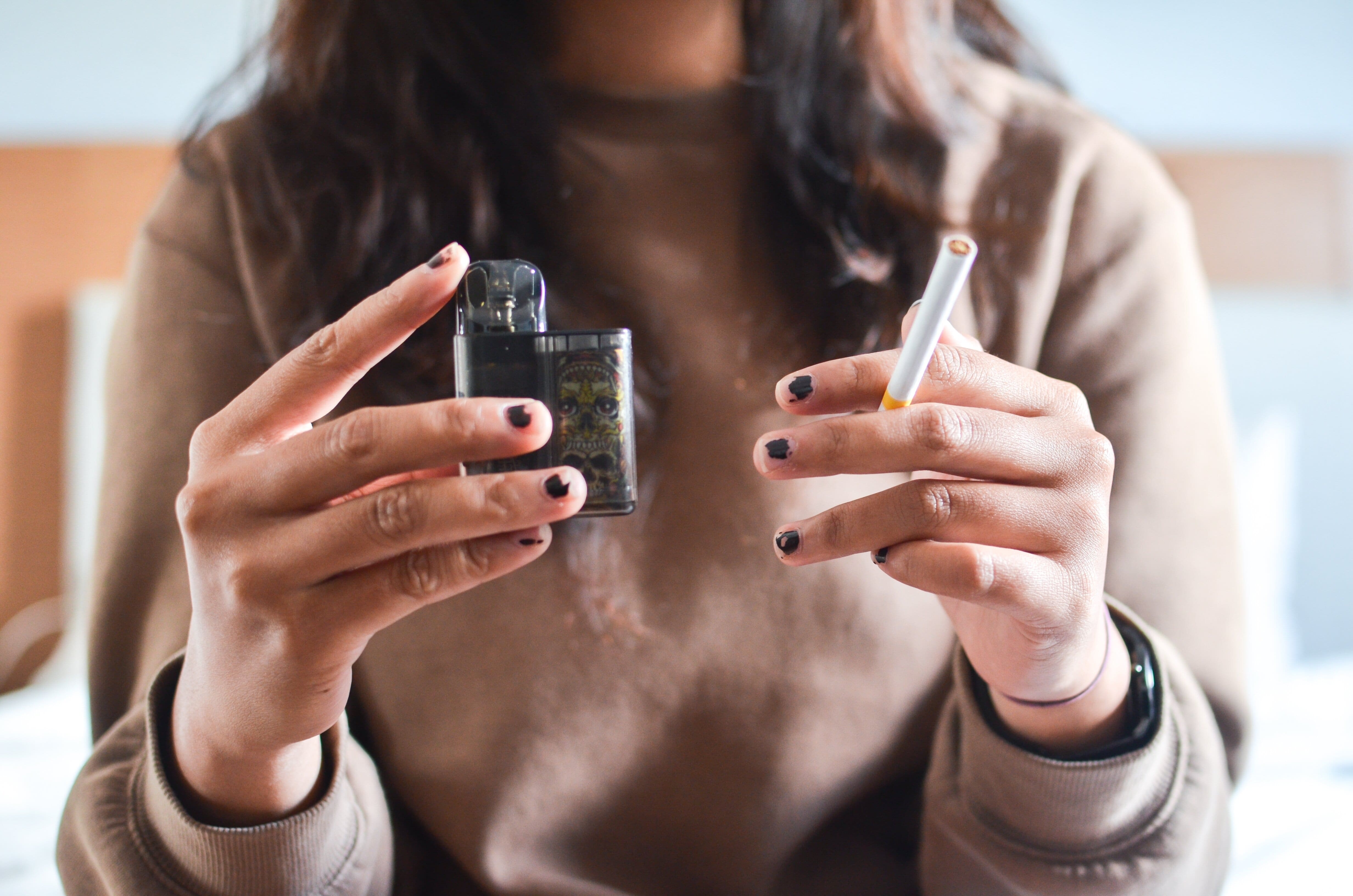 Woman holding a cigarette and a vape