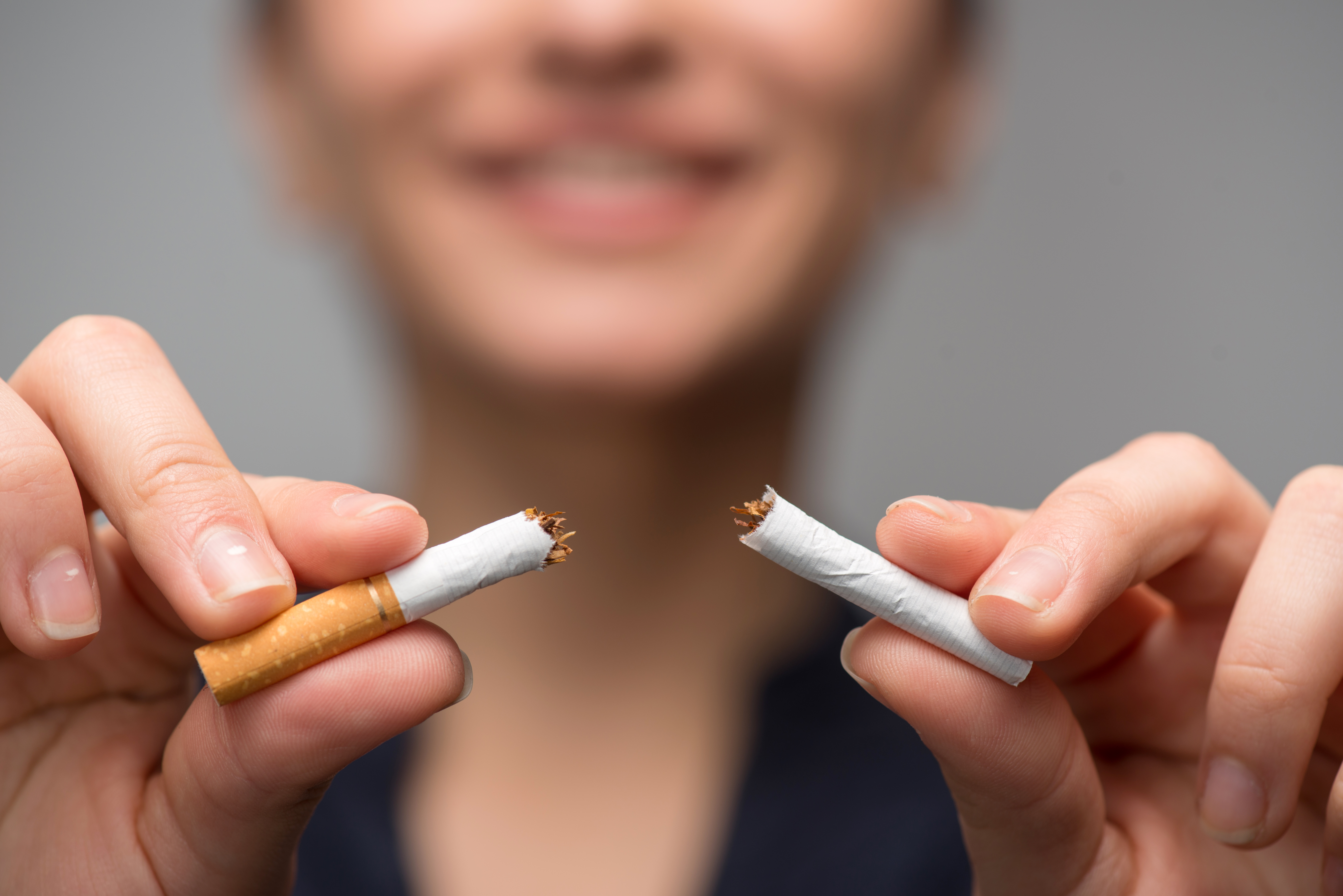 Young woman smiles and breaks cigarette in half