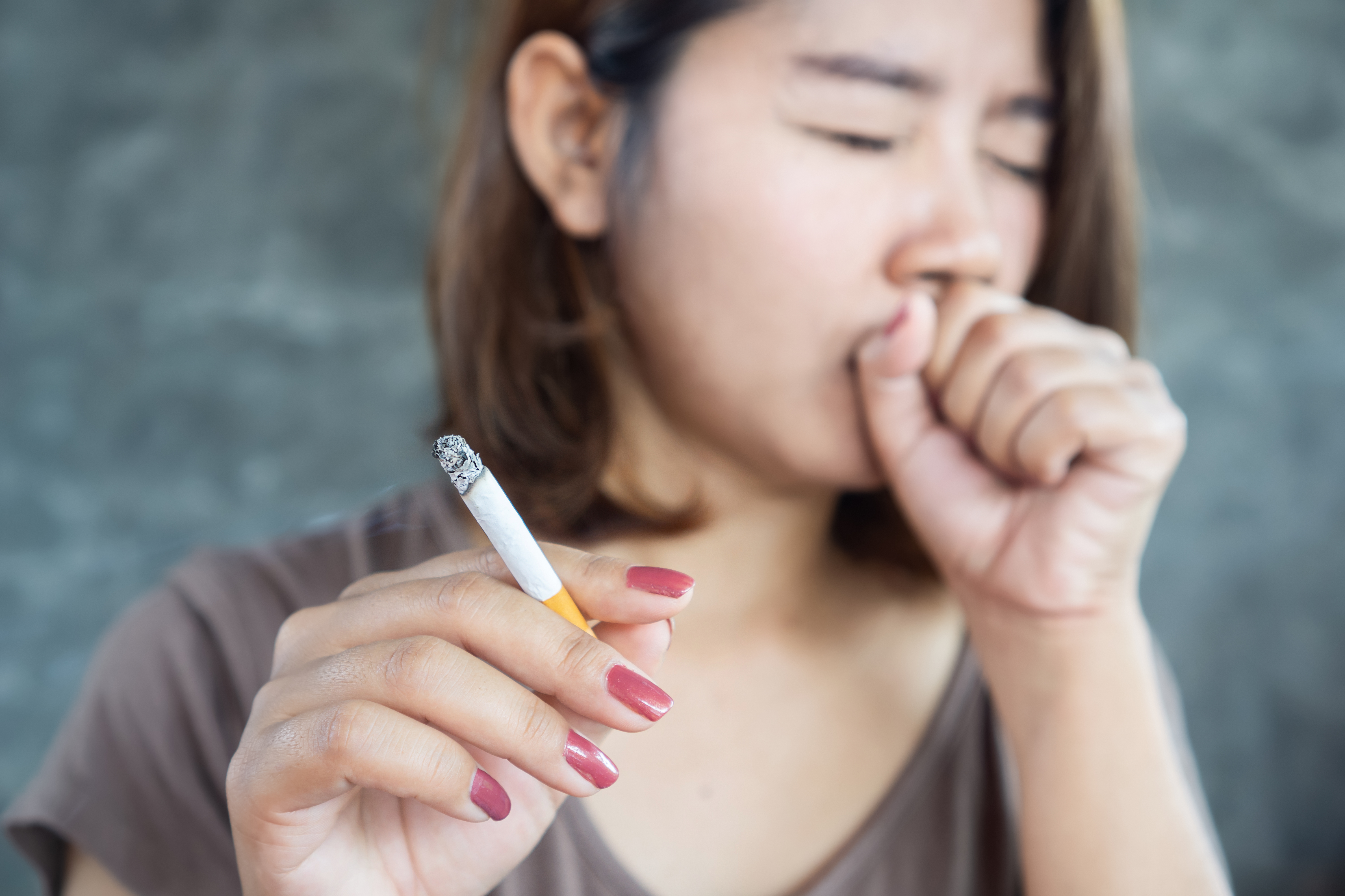 Woman holding a cigarette and coughing