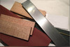 DIY knife making kit components including blade steel, spacers, and sandpaper