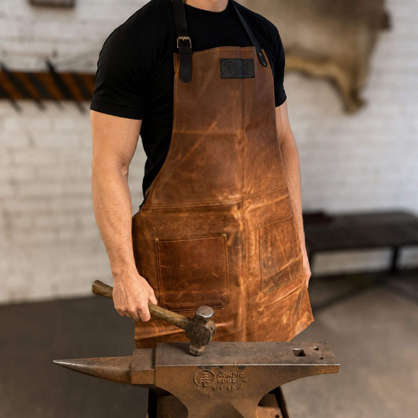 Nordic Edge brown cowhide leather apron worn at a blacksmithing anvil