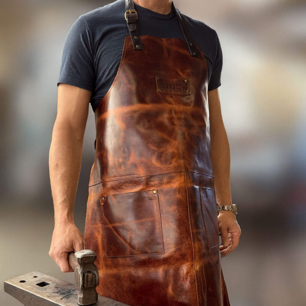 Blacksmith leather apron in chestnut brown with pockets and straps, worn in workshop