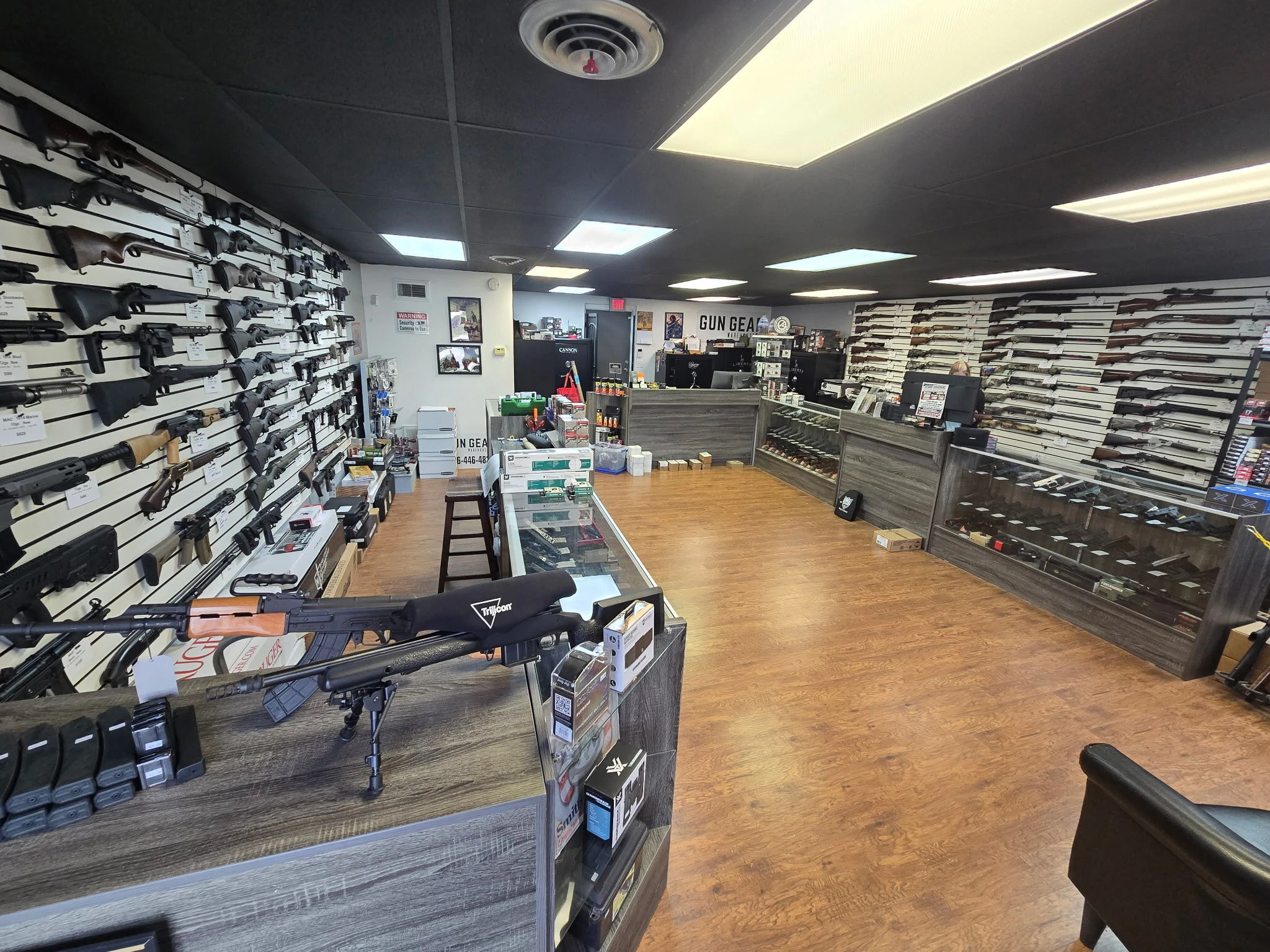 Inside the Gun Gear Warehouse store in Oak Grove, Missouri, with rifles and shotguns on the walls and handguns in the display cases