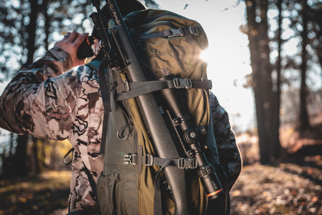Hunter with precision rifle in mountain terrain