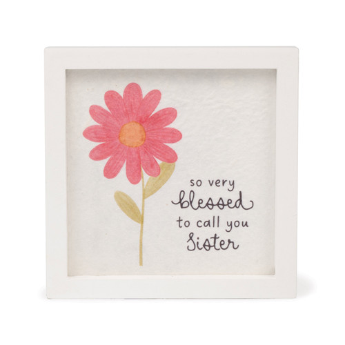 A square white-framed sign with a watercolor-style illustration of a pink daisy and the text, "so very blessed to call you Sister."