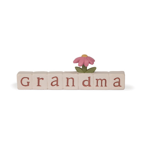 A hand-painted resin decorative block from Blossom Bucket spelling 'Grandma' in rose-colored letters on cream tiles, topped with a single pink flower and green leaves.