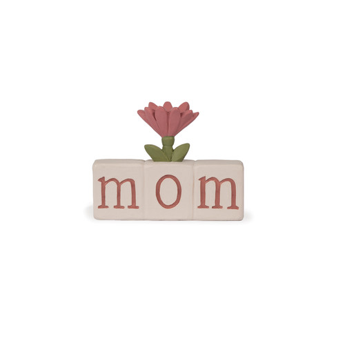 A hand-painted resin decorative block from Blossom Bucket spelling 'mom' in rose-colored letters on cream tiles, topped with a single pink flower and green leaves.