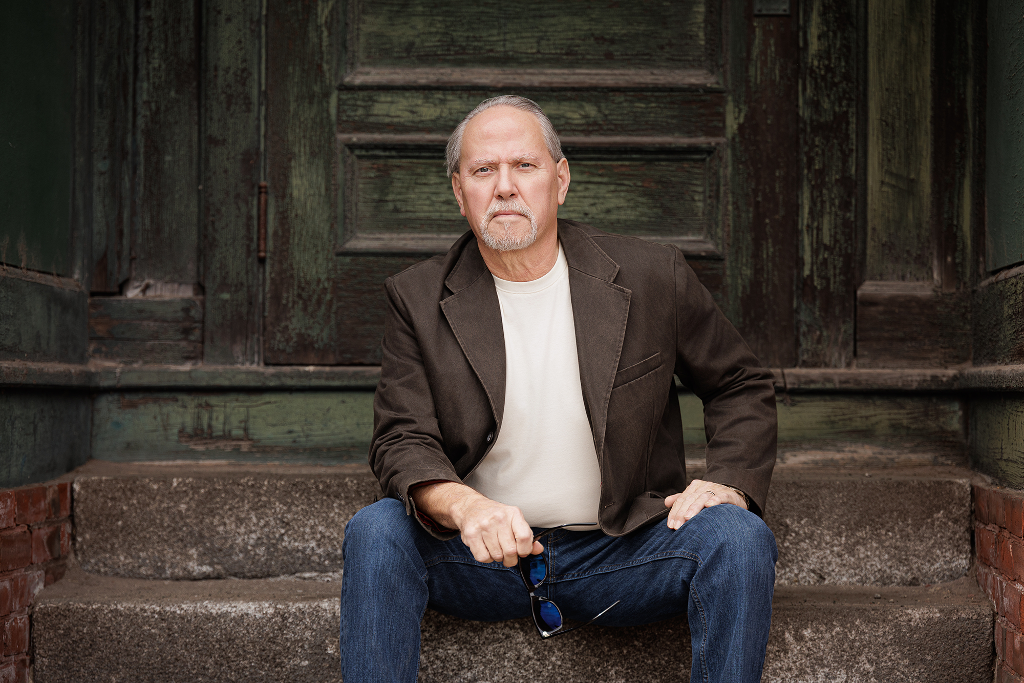 Man sits to enjoy the day in a comfortable Egyptian cotton t-shirt with jeans and a leather jacket