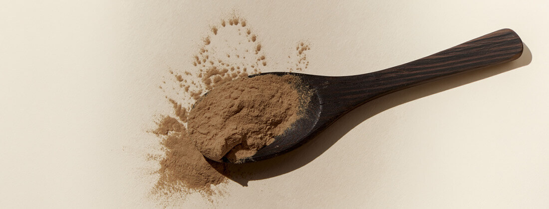 A spoon full of a brown powder on a beige surface